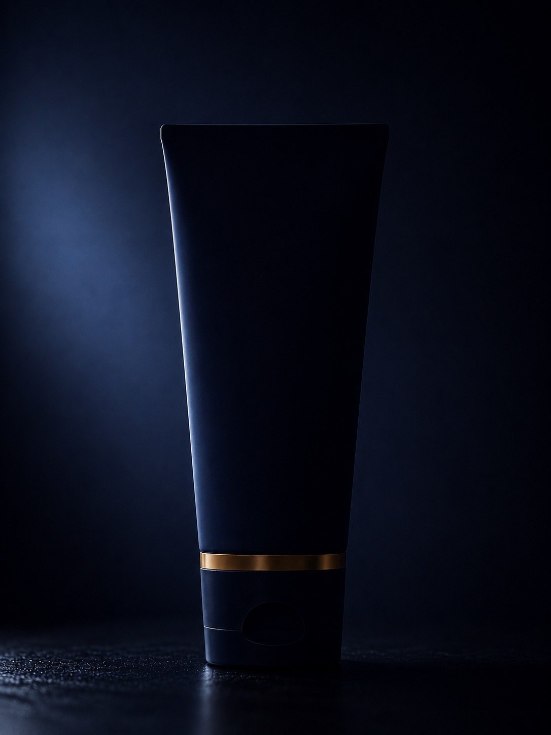 The Cleanser, a navy tube with a gold band, standing on a dark plate